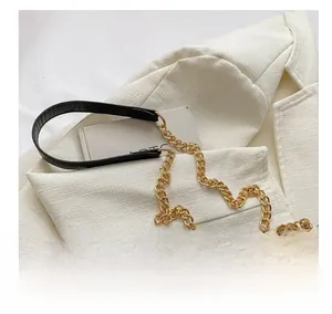 Detail of the black quilted shoulder bag featuring premium gold chain strap on blazer
