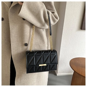 Close-up of geometric quilted texture and gold metal chain on black crossbody bag