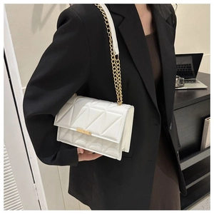 Close-up of white quilted leather bag with gold hardware worn by model on shoulder