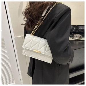 Detail of white quilted geometric shoulder bag with gold chain and metal bar accent