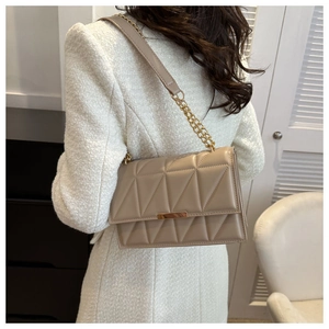 Detail of light beige quilted chain bag featuring elegant gold metal clasp and trim