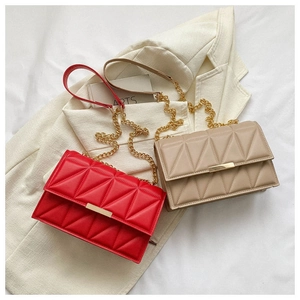 Detail of red and beige quilted chain crossbody bags with elegant gold metal buckles