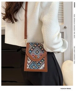 Detailed side view of a colorful ethnic woven crossbody phone bag with brown leather trim