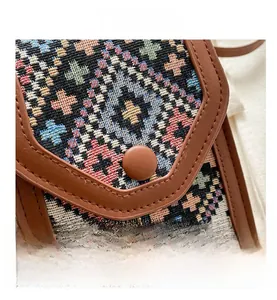 Detail view of ethnic woven fabric pattern with brown leather trim and magnetic closure