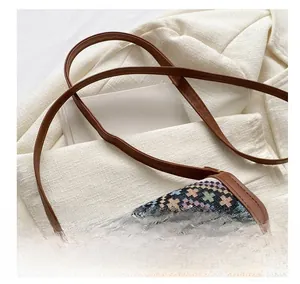 Close-up of ethnic style woven crossbody bag with brown leather strap on blazer