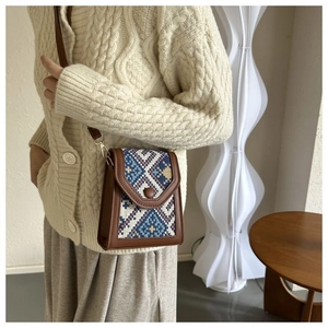Ethnic crossbody bag with geometric weave pattern and brown leather strap on model