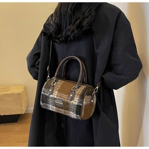 Detail of checkered wool boston bag featuring leather handles and adjustable shoulder strap