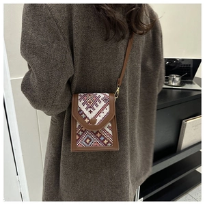 Detail of ethnic geometric woven fabric on a brown leather crossbody phone bag for women
