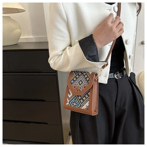 Detailed shot of ethnic geometric weaving on brown leather crossbody phone bag with chain
