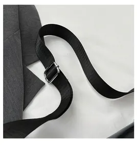 Détail de la bandoulière noire tissée réglable avec boucle métallique argentée sur le sac