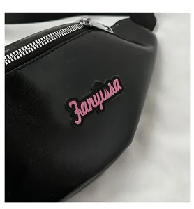 Gros plan sur le sac ceinture en cuir PU noir avec logo rose 3D et fermeture éclair en métal