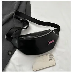 Détail du sac banane en cuir PU noir avec fermeture éclair argentée et écusson logo