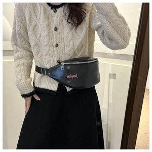Détail d'un sac ceinture en cuir noir avec logo rose et zip argenté porté par un mannequin