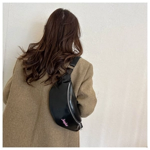 Détail du sac ceinture en similicuir noir avec logo rose et fermeture éclair argentée