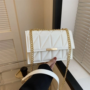 Elegant white quilted crossbody bag with gold chain strap and metal lock in a stylish setting