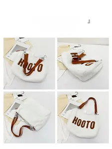 Detail view of large white plush tote bag with brown HOOTO lettering and leather straps