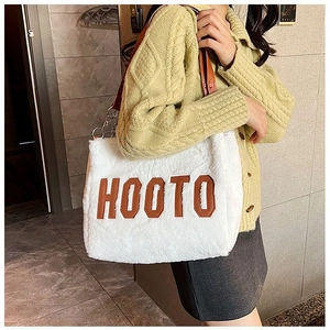 Close-up of white plush tote bag with HOOTO leather lettering and metal chain strap