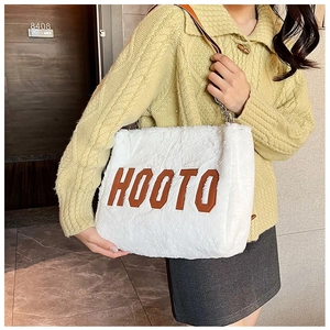 Detail view of plush white tote bag with HOOTO letter patch and brown leather strap