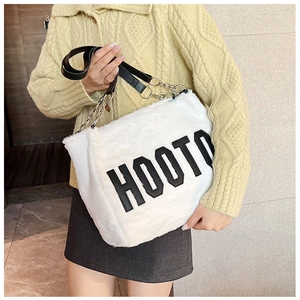 Close-up of white plush tote bag with black HOOTO lettering and metal chain strap