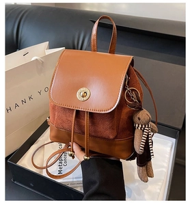 Detail of brown leather backpack featuring a gold twist lock and cute bunny pendant