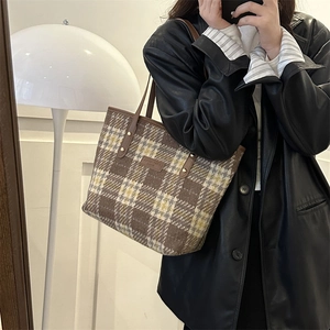 Dettaglio della borsa tote in lana a quadri con tessuto a trama e etichetta in pelle