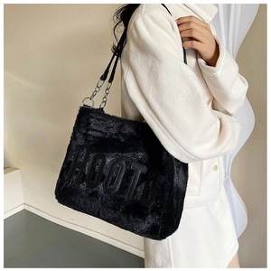 Detail of black plush tote bag with faux fur texture and silver metal chain strap