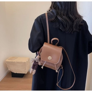 Detailed back view of a vintage brown leather mini backpack with a plush rabbit charm