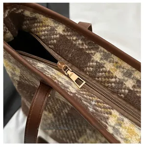 Dettaglio della cerniera in metallo dorato su una borsa tote in tweed a quadri