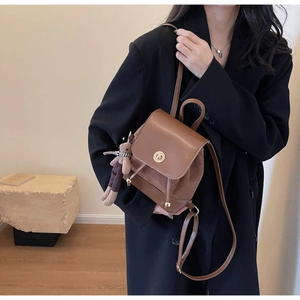 Detail of vintage brown leather backpack with gold clasp and cute bear charm pendant