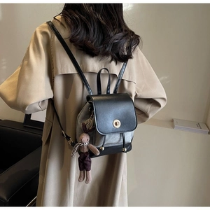 Detail of a mini canvas backpack with black leather flap and cute rabbit charm