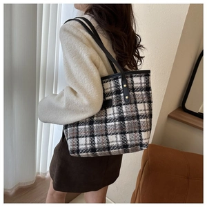 Dettaglio della borsa tote in tweed a quadri con tracolla in pelle e rivetti