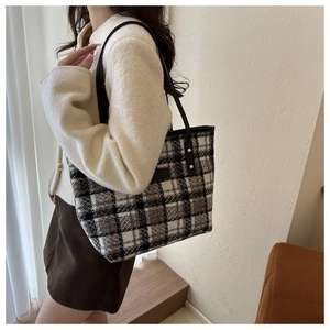 Dettaglio di una borsa tote in tweed a quadri con tracolla indossata in un contesto autunnale