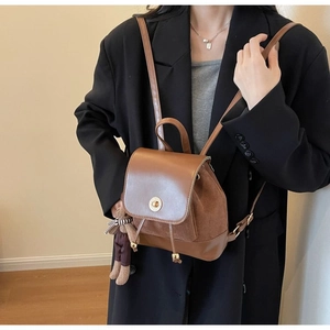 Detail of retro brown leather backpack featuring a vintage metal lock and a cute bear charm