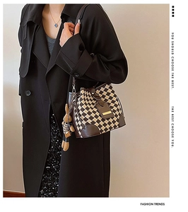 Detail of retro plaid bucket bag with leather trim and brown plush rabbit charm