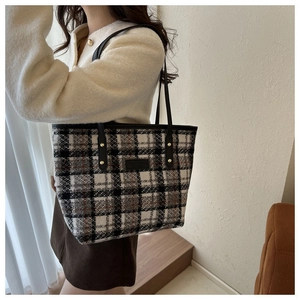 Dettaglio della borsa tote in tweed a quadri con tracolla e borchie dorate