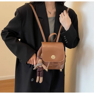 Detail of brown mini backpack with drawstring closure, gold knob, and cute rabbit charm