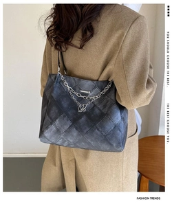 Quilted tote bag with silver chains shown as a shoulder bag on a model wearing a wool coat