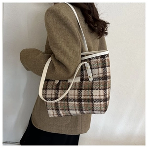 Dettaglio della borsa tote in lana a quadri con finiture in pelle ed etichetta