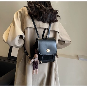 Detail of black leather backpack with gold clasp and a cute plush rabbit pendant charm