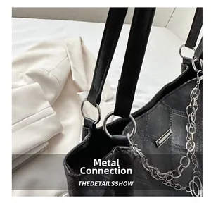 Detailed shot of silver metal rings and side chain on a black quilted tote bag