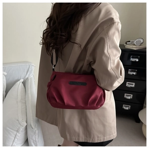 Detail of burgundy pleated crossbody bag with JINGPIN label and soft fabric texture