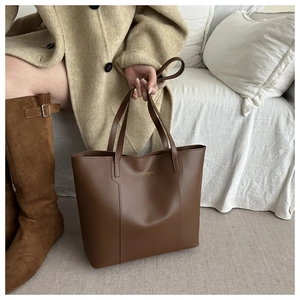 Détail d'un sac cabas en cuir marron avec logo doré et finition texturée élégante