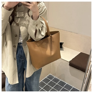 Détail d'un sac cabas en similicuir marron avec logo discret lors d'une séance photo urbaine
