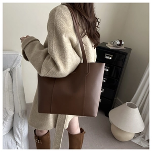 Détail du sac cabas élégant en cuir marron foncé avec coutures verticales et logo doré