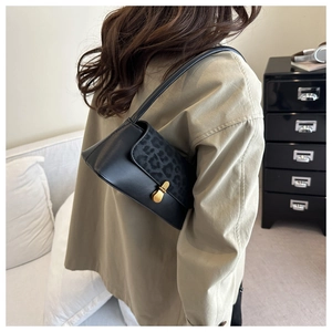Close-up of black underarm bag featuring leopard print flap and gold twist-lock