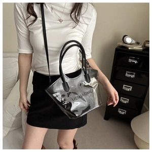 Sac fourre-tout transparent en PVC avec poignées noires et bandoulière porté par un mannequin