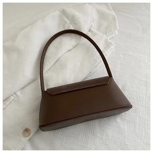 Detail of dark brown baguette bag showing matte faux leather texture and minimalist flap