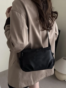 Minimalist black nylon shoulder bag with pleated design and adjustable long strap for women