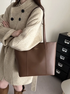 Grand sac cabas élégant en cuir marron foncé porté par un mannequin en manteau de laine beige