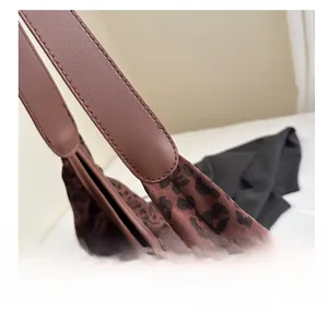 Detail showing the stitching craftsmanship of leopard print tote bag with leather strap